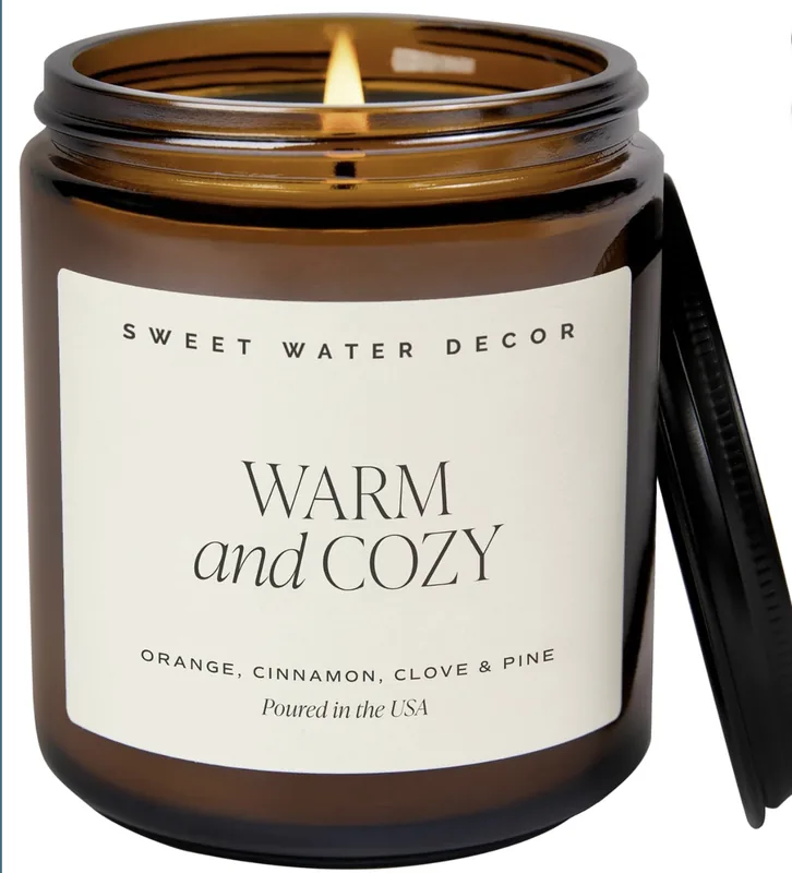 Sweet Water Decor Warm and Cozy candle in a 9-ounce amber jar